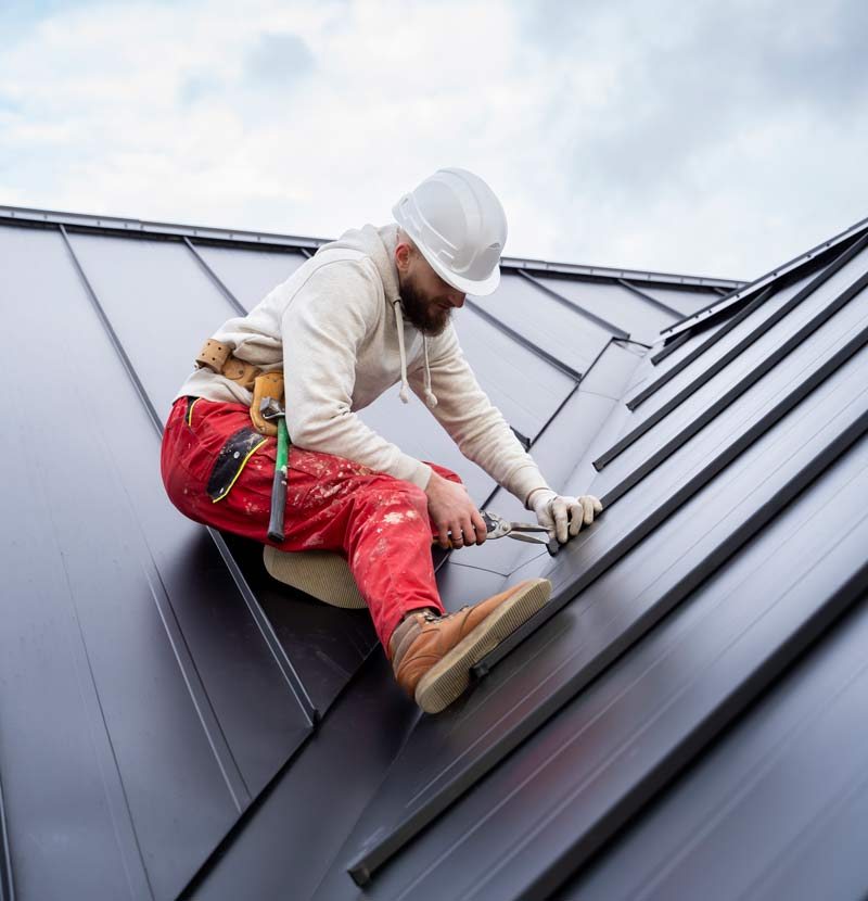 Full shot of a roofer in a helmet working on a roof