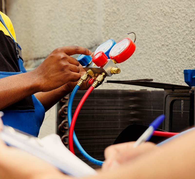 HVAC technician checking refrigerant gauges on a service call, the kind of job gravityGone's HVAC marketing helps keep booked