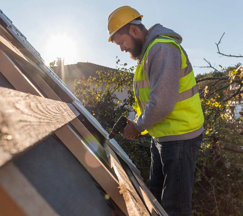 Roofer using a drill to install shingles on a roof, the kind of job gravityGone's roofing marketing helps keep booked