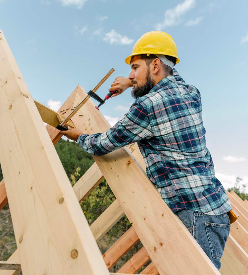 Roofing worker in a hard hat building a roof on a house
